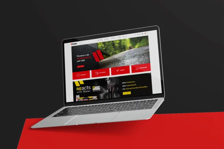 Laptop mit der Vialit Website, die Produkte und Dienstleistungen im Bereich Straßenbau präsentiert, auf rotem Hintergrund.
